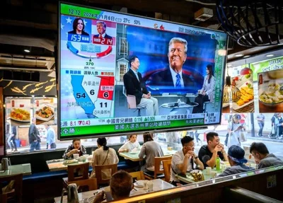 A flat-screen television, displaying a smiling Mr. Trump accompanied by election results in Chinese, hangs above a half-dozen people sitting in a casual restaurant.