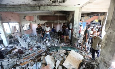 People stand among rubble inside a wrecked building