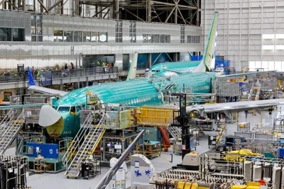 A green plane being assembled, with cranes and staircases surrounding it.