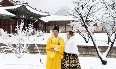 Thai tourists wearing Korean traditional Hanbok dresses take pictures amid snowfall at Gyeongbokgung Palace in Seoul