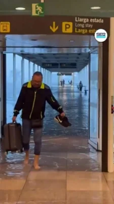 A man is seen taking his shoes off and wading through the departures hall at El Prat airport