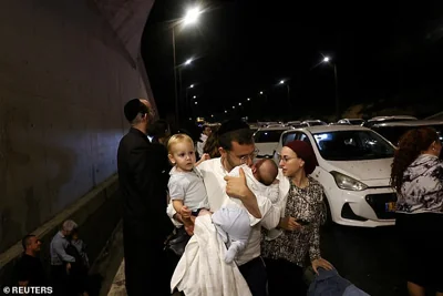 A man holds children as people take cover during an air raid siren in central Israel after Iran fired off a salvo of missiles on Tuesday night