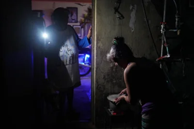 IN THE DARK A woman boils water while her companion lights her with a mobile phone during a nationwide blackout caused by a power grid failure in the city of Matanzas, west-central Cuba, on Oct. 18, 2024. AFP PHOTO