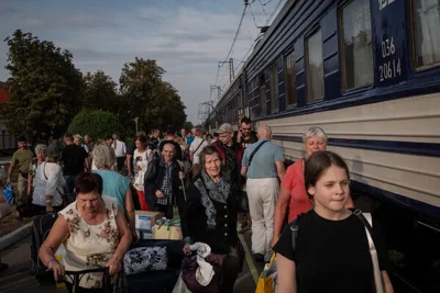 People with luggage walking next to a train.