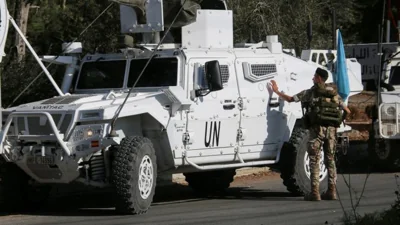 A Lebanese army soldier stands near UN peacekeepers (UNIFIL) vehicles