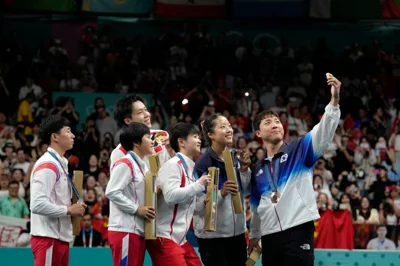 South Korea's Lim Jonghoon, right, takes a selfie with North Korea's Ri Jong Sik, left, and Kim Kum, second left, China's Wang Chuqin, background, and Sun Yingsha, center, and his teammate Shin Yubin, right, and Lim Jonghoon during the medal ceremony at the 2024 Summer Olympics, Tuesday, July 30, 2024, in Paris, France. (AP Photo/Petros Giannakouris)