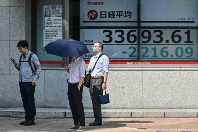 Three people stand outside a building. There are displays in the window showing numbers. 