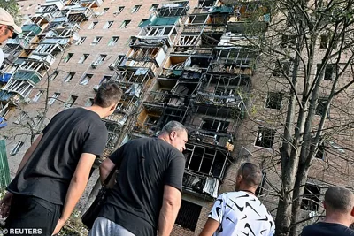 People gather in the courtyard of a damaged multi-storey residential building in the course of Russia-Ukraine conflict in Kursk, Russia