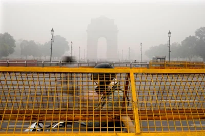 A commuter drives near New Delhi's iconic India Gate amid a thick layer of smog