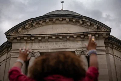 A woman with her hands raised, facing Congregation Beth Elohim.