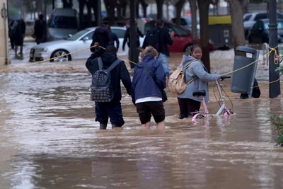 Residents use a makeshift pulley to haul themselves out of knee-deep water