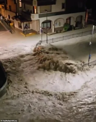 The flooding in Noasca, Italy is seen above with raging water flooding the roads