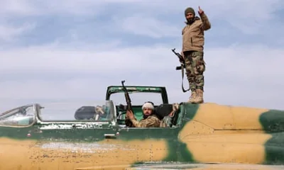 Anti government fighters gesture as they check a Syrian army jet after they took over a military airbase near the central city of Hama