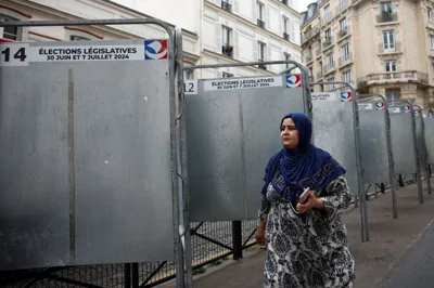 A woman passes by the election boards placed ahead of the June 30 and July 7 French parliamentary elections, in Paris, France, June 19, 2024. REUTERS/Benoit Tessier