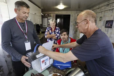 A man casts his ballot at his home as a member of an election commission helps him in Kursk, September 7, 2024