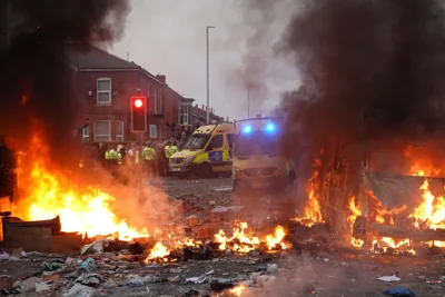 Riot police hold back protesters near a burning police vehicle in Southport after disorder broke out on Tuesday