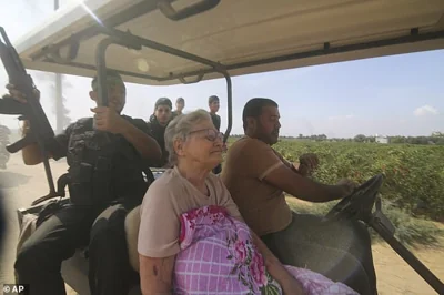 Palestinians transport a captured Israeli civilian, center, from Kfar Azza kibbutz into the Gaza Strip on Saturday, Oct. 7, 2023