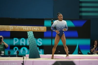 Simone Biles standing beside the balance beam. 