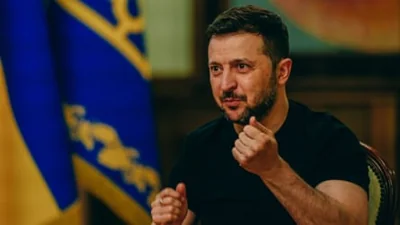 Volodymyr Zelenskyy holds up both fists and gesticulates as he speaks