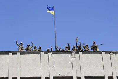 In this photo taken on Saturday, July 5, 2014, Ukrainian soldiers raise a Ukrainian flag over the city government headquarters in the city of Slovyansk, eastern Ukraine.