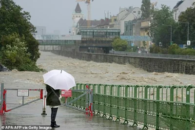 AUSTRIA: A pedestrian looks at the high level of the Wien river in Hutteldorf, Vienna