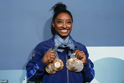 Simone Biles, of the United States, holds up her medals at the 2024 Summer Olympics