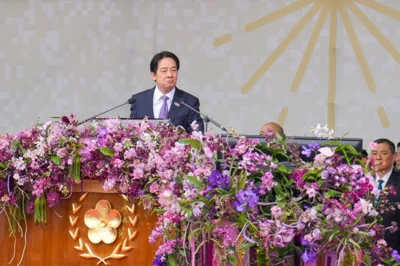 William Lai Ching-te. He is standing behind a lectern garlanded with pink flowers