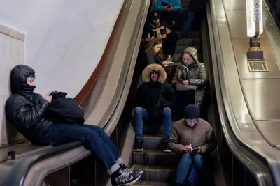 People sitting on and around an escalator.