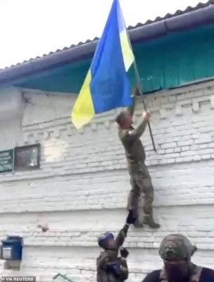 A Ukrainian soldier raises a Ukrainian flag in Guevo, Kursk Oblast, Russia released August 11, 2024 in this still image obtained from a social media video