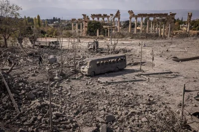 Damaged cars and debris near an ancient Roman temple. 