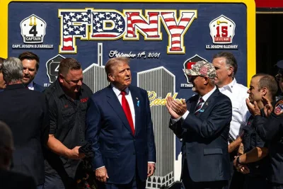 Donald Trump stands with a handful of firefighters with a Sept. 11 memorial mural depicting the Twin Towers behind him.