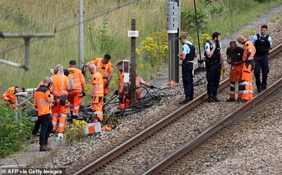 Railway employees and French gendarmes inspect the scene of a suspected attack on the high speed railway network at Croiselles in northern France on Friday