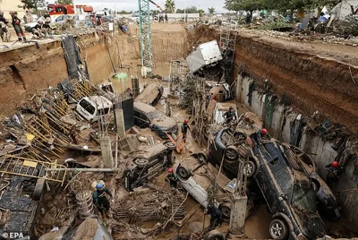 Cars piled up in a ditch at a construction site after being swept off the road by powerful floods