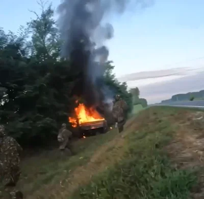 A Russian truck up in flames surrounded by Ukrainian special forces