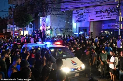 An ambulance makes it way through the crowd.  Tonight, video footage showed an apartment block ablaze and a sense of panic in the southern suburb of Haret Hreik