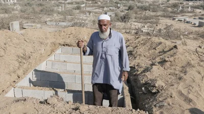 Palestinian grave digger Sa'di Baraka pauses while digging new graves in a cemetery in Deir al-Balah, Gaza Strip, 2 August 2024