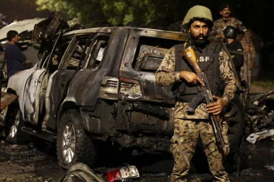 A soldier standing guard near a burned car targeted in an attack near Karachi airport