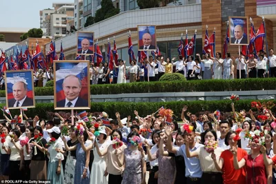 People wave to the motorcade carrying North Korea's leader Kim Jong Un and Russian President Vladimir Putin during a welcoming ceremony at Kim Il Sung Square in Pyongyang on June 19, 2024