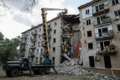 A crane works on a damaged five-story apartment building.