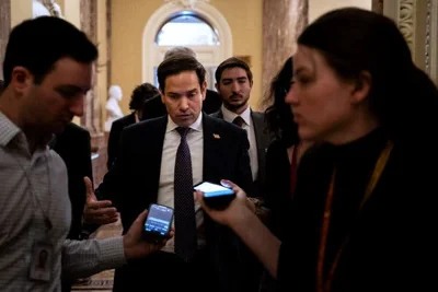 Senator Marco Rubio of Florida walking toward two people who are holding phones out to record his comments. 