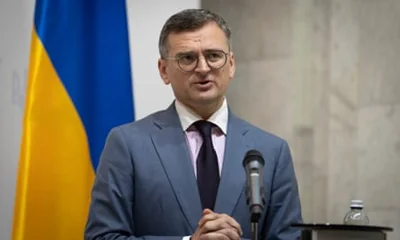 Former Ukrainian foreign minister Dmytro Kuleba stands in front of a Ukrainian flag during a press conference. 