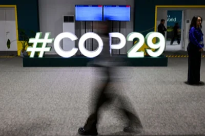 Attendees walk past the COP29 logo