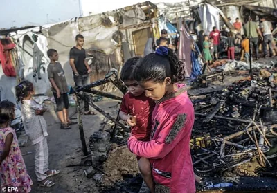 Palestinians inspect destroyed makeshift tents at a camp for internally displaced people on the premises of al-Aqsa Hospital, after the area was hit by an Israeli air strike, in Deir al Balah, central Gaza Strip, 14 October 2024