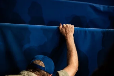 A photograph, from the back, of a supporter of Kamala Harris in a blue cap.