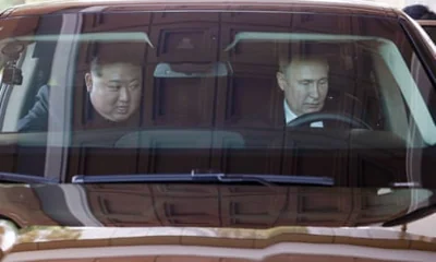 Closeup of Vladimir Putin and Kim Jong-un in car with Putin driving 