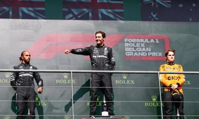 George Russell heads the podium after the Belgium GP, alongside second-placed Lewis Hamilton (left) and Oscar Piastri