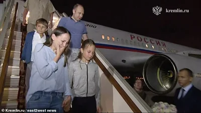 The Dultsev family are seen exiting the plane to meet Putin on the tarmac in Moscow
