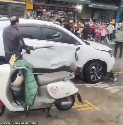 An enranged bystander smashes the window of the car that ran down children and adults outside a school