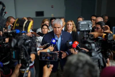 José Raúl Mulino speaks to a scrum of people holding microphones and cameras.