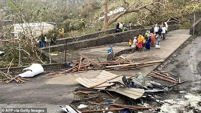 A photo taken on December 15, 2024 shows residents sitting by a road among piles of debris of metal sheets and wood after the cyclone Chido hit France's Indian Ocean territory of Mayotte